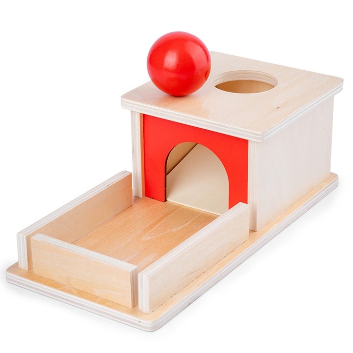 jeu pour enfant en bois avec une balle rouge, une boite et un trou pour mettre la balle.