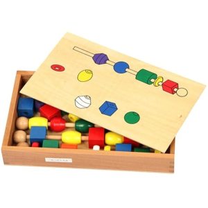 Jeu d'assemblage de perles colorées en bois sur un bâton, situées de formes et couleurs différentes dans une boite en bois
