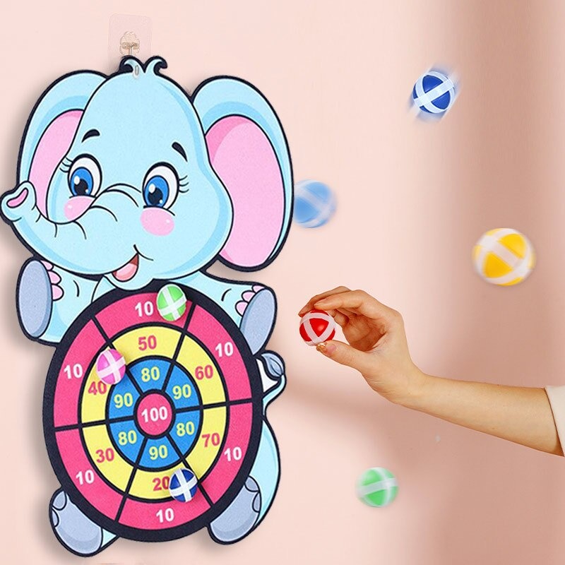 un jeu de tir de cible en forme d'éléphant fixé à un mur rose, on voit une main qui jette
