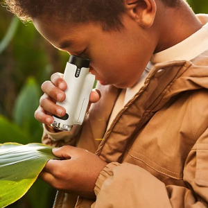 Microscope enfant LED portable et ergonomique en plastique dans les mains d'un garçon avec veste marron utilisant le microscope