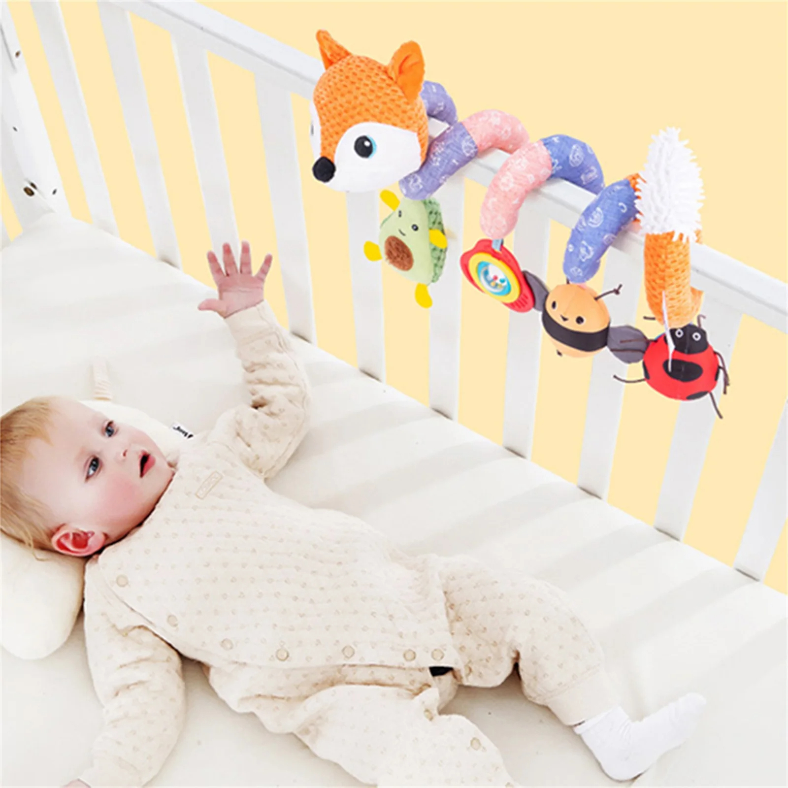 Spirale d'activité bébé en forme de renard en coton et polyester sur un lit avec un bébé jouant sur fond beige
